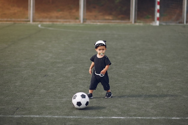 Niño pequeño jugando al fútbol en un campo de deportes