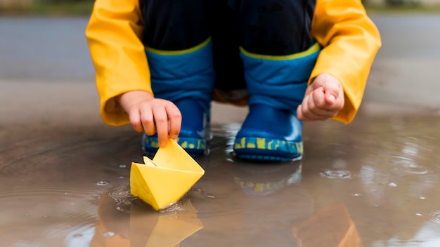 Niño pequeño jugando con un primer plano de barco de papel