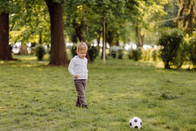 Niño pequeño lindo jugar un fútbol al aire libre