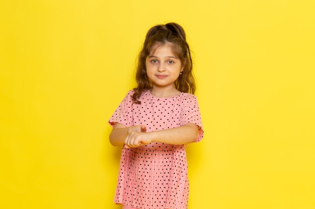 Un niño pequeño lindo de vista frontal en vestido rosa apuntando a su muñeca