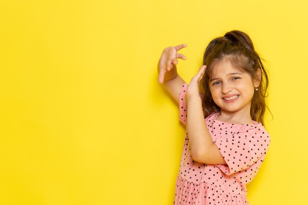 Foto gratuita un niño pequeño lindo de vista frontal en vestido rosa cubre su rostro