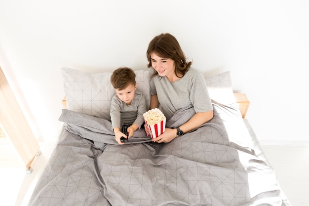 Foto gratuita niño pequeño con mamá acostada en la cama