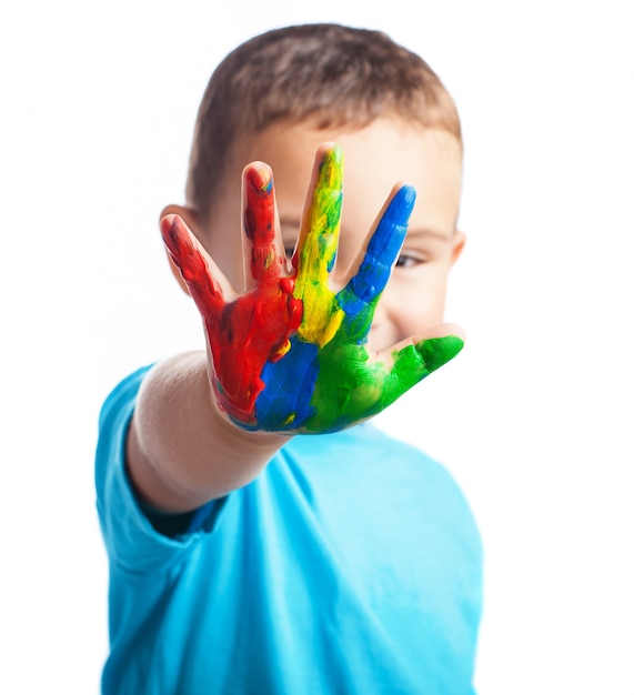 Niño pequeño con una mano llena de pintura tapándose la cara