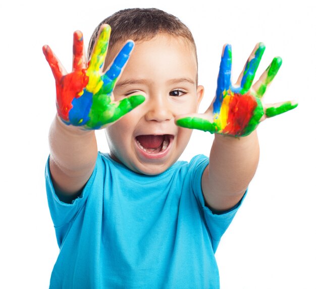 Niño pequeño con las manos llenas de pintura y con la boca abierta