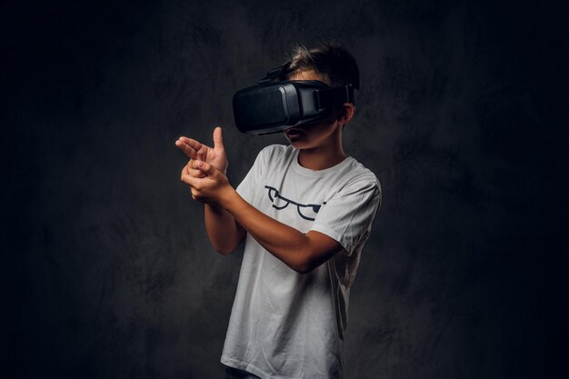 Un niño pequeño y moderno está jugando un nuevo videojuego de disparos usando gafas especiales de realidad virtual.