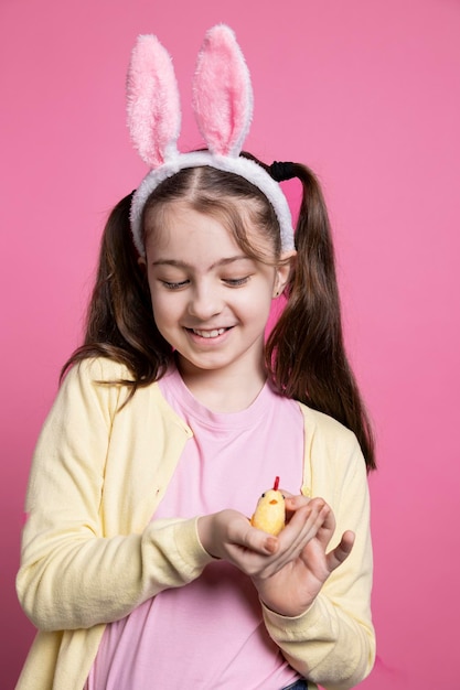 Foto gratuita un niño pequeño mostrando un lindo juguete de pollo de peluche en el estudio