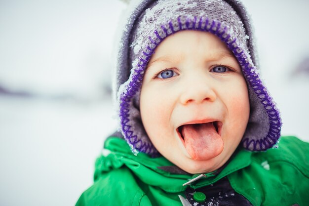 El niño pequeño se para en la nieve