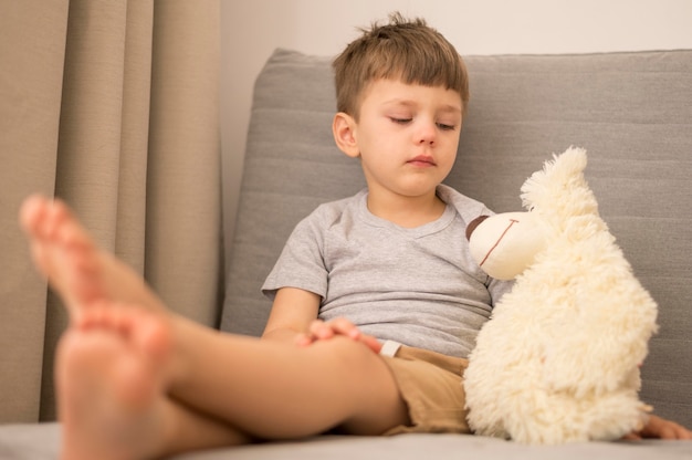 Foto gratuita niño pequeño con oso tedy en casa