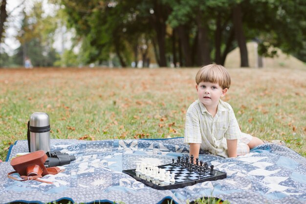 Foto gratuita niño pequeño en picnic jugando al ajedrez