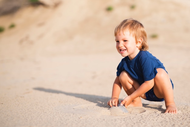 Niño pequeño en la playa mirando a otro lado