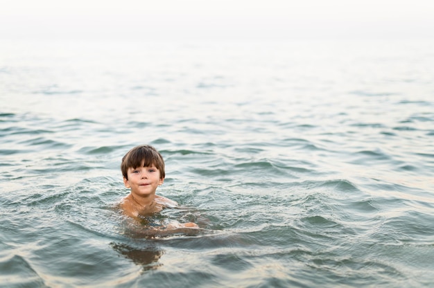 Niño pequeño posando en el mar