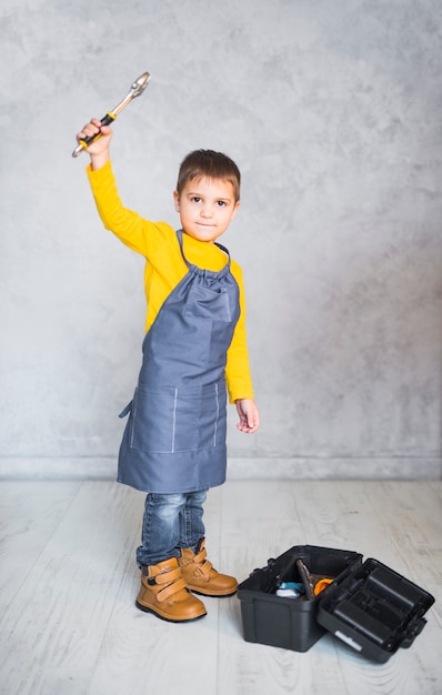 Foto gratuita niño pequeño, posición, con, llave inglesa