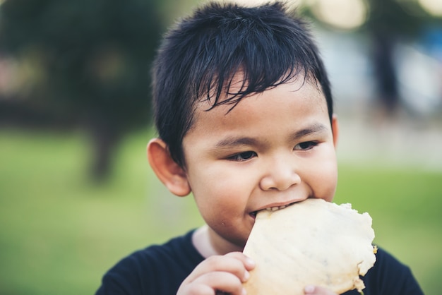 Foto gratuita niño pequeño que come el emparedado del rollo de pan fresco de la comida