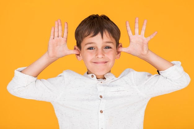 Foto gratuita niño pequeño que es tonto con fondo naranja