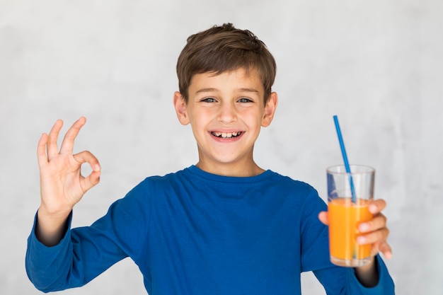 Foto gratuita niño pequeño que le gusta su jugo de naranja