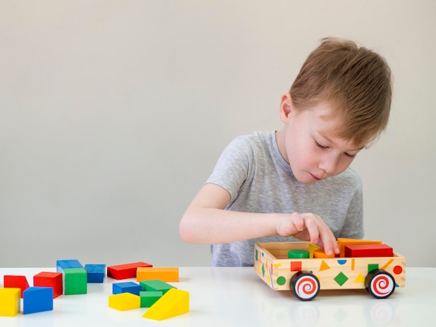 Niño pequeño que juega con el coche de madera