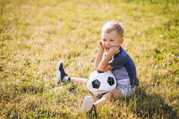 Niño pequeño que juega a fútbol en el campo