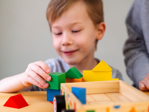 Niño pequeño que juega con el juego de formas coloridas en el interior