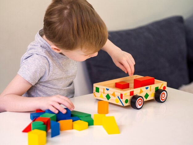 Niño pequeño que juega con el juguete interesante del coche de madera