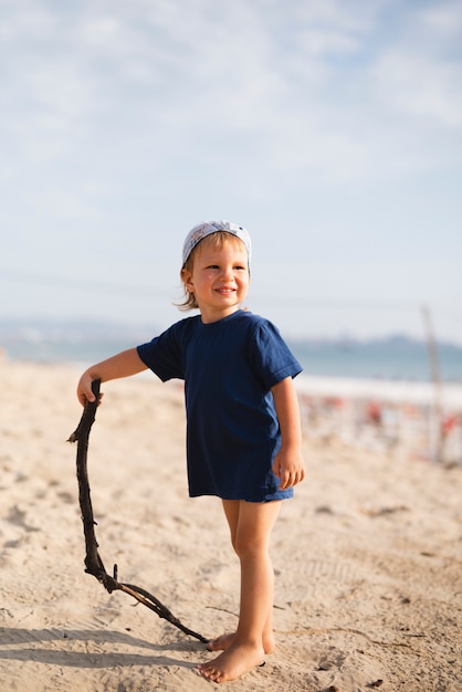 Foto gratuita niño pequeño que juega con el palillo en la playa