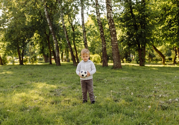 Niño pequeño que juega la pelota de fútbol al aire libre