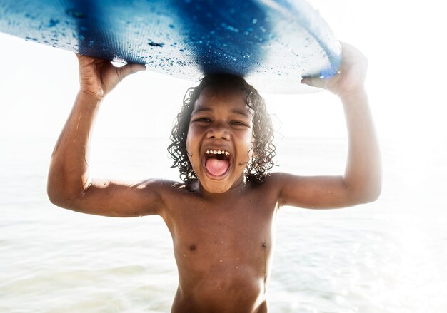 Un niño pequeño que lleva una tabla de surf.