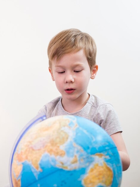 Niño pequeño que mira en el globo