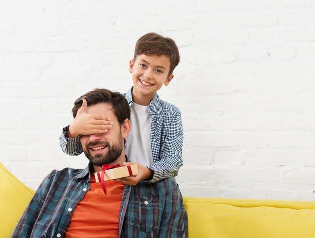 Niño pequeño que ofrece un regalo a su padre