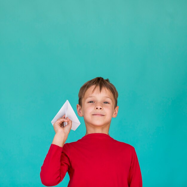 Niño pequeño que sostiene un aeroplano de papel
