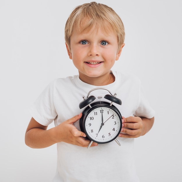 Foto gratuita niño pequeño que sostiene un reloj