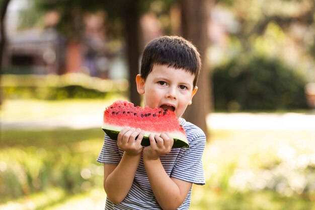 Niño pequeño que tiene sandía al aire libre