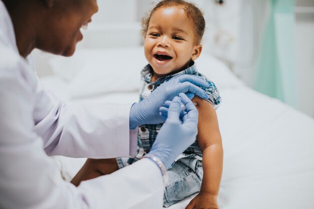 Niño pequeño recibiendo una vacuna por parte de un pediatra