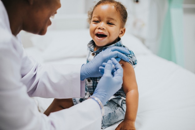 Niño pequeño recibiendo una vacuna por parte de un pediatra