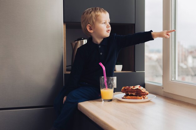 Niño pequeño señalando por la ventana