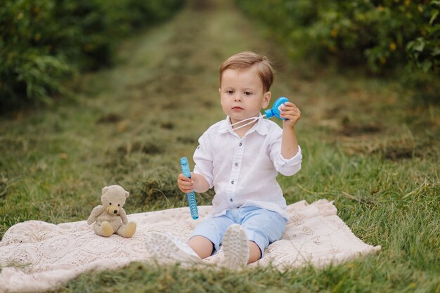 Niño pequeño sentado en cuadros de picnic en el jardín de la cabaña