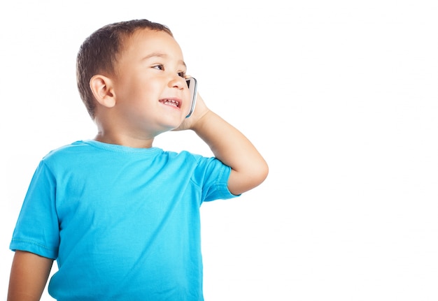 Niño pequeño sonriendo mientras habla por un teléfono