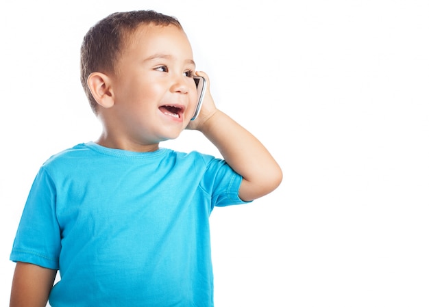 Niño pequeño sonriendo mientras habla por un teléfono