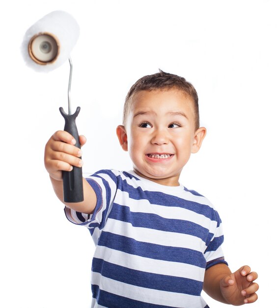 Niño pequeño sonriendo y sujetando en alto un rodillo de pintura