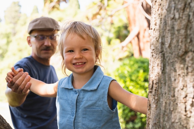 Niño pequeño sonriente explorando árboles con el abuelo