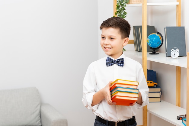 Foto gratuita niño pequeño sonriente que sostiene la pila de libros