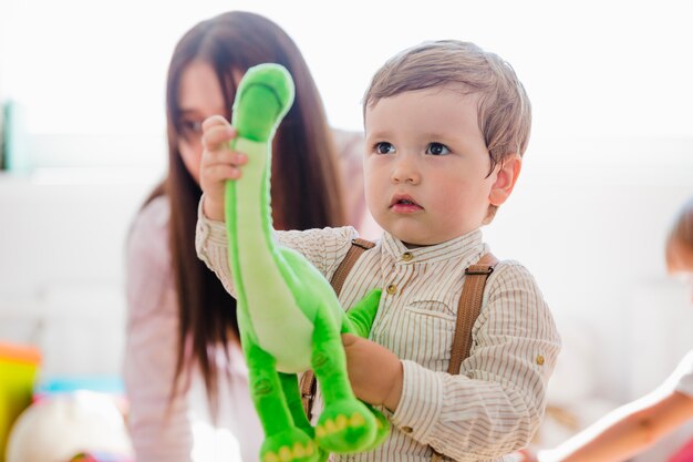 Niño pequeño sosteniendo el juguete verde del dinosaurio