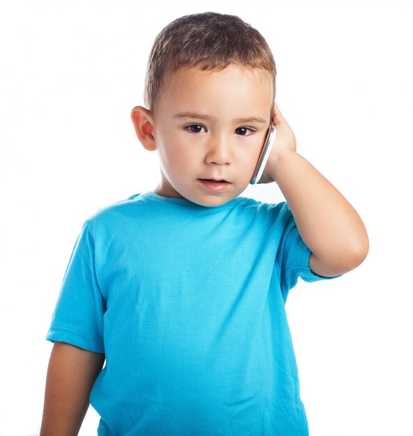 Niño pequeño con un teléfono en la oreja