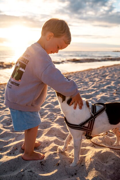 Niño pequeño de tiro completo acariciando a un perro lindo