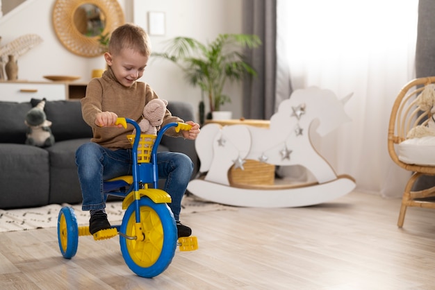 Niño pequeño de tiro completo sentado en un triciclo en casa