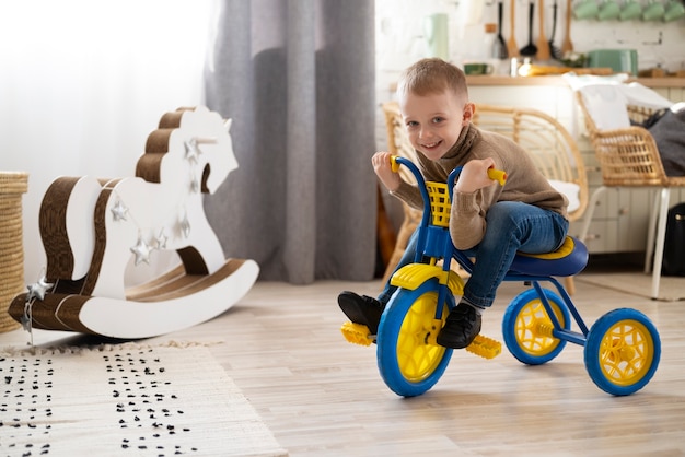 Niño pequeño de tiro completo sentado en triciclo