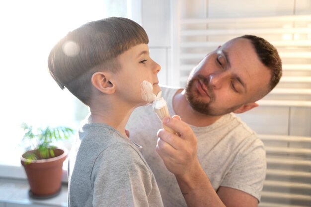 Niño pequeño de tiro medio aprendiendo a afeitarse