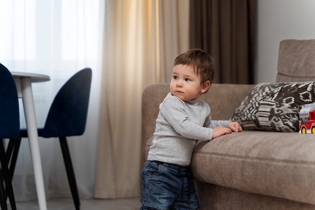 Niño pequeño de tiro medio de pie en la sala de estar