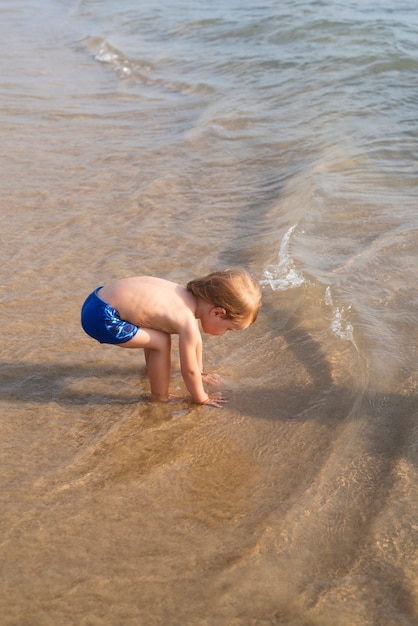 Foto gratuita niño pequeño con traje de baño en la playa