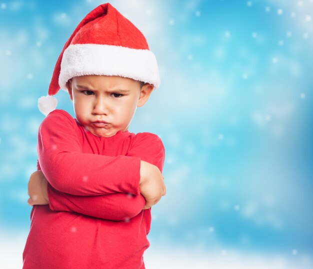 Niño pequeño triste llevando gorro de santa