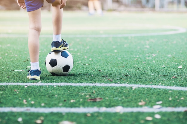 Niño de pie con la pelota en el campo de fútbol listo para comenzar o jugar un nuevo juego